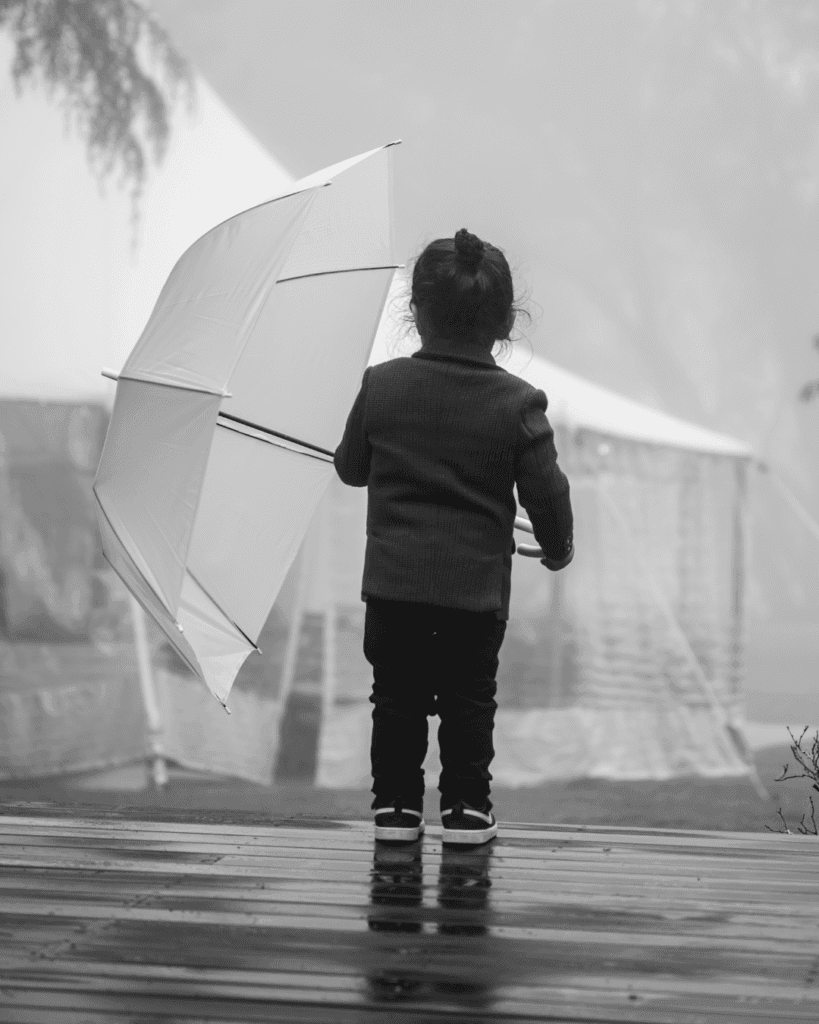 child standing in rain with umbrella photoshoot